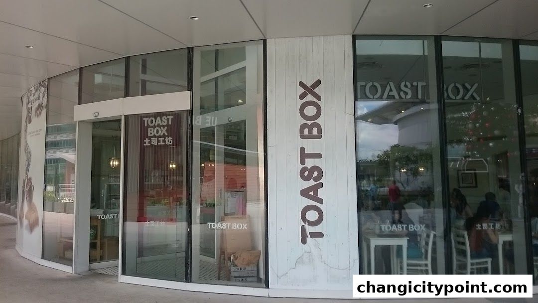 The exterior of a Toast Box cafe with large glass windows and signage.
