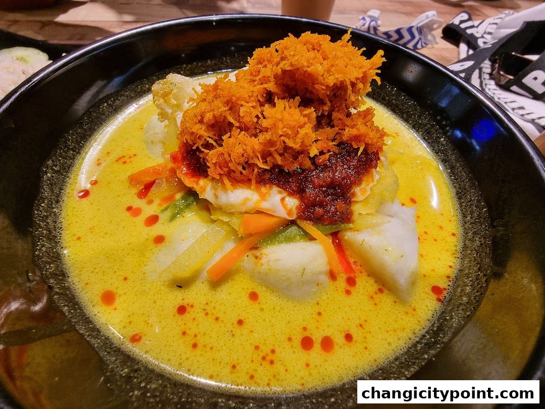 A close-up of a delicious bowl of Lontong with rich curry and shredded toppings.