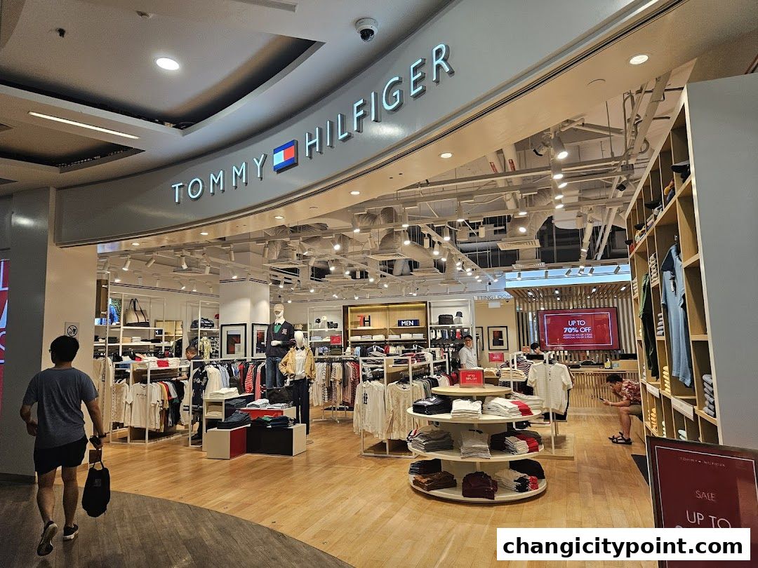 Interior view of a Tommy Hilfiger store with clothing displays and sale signage.