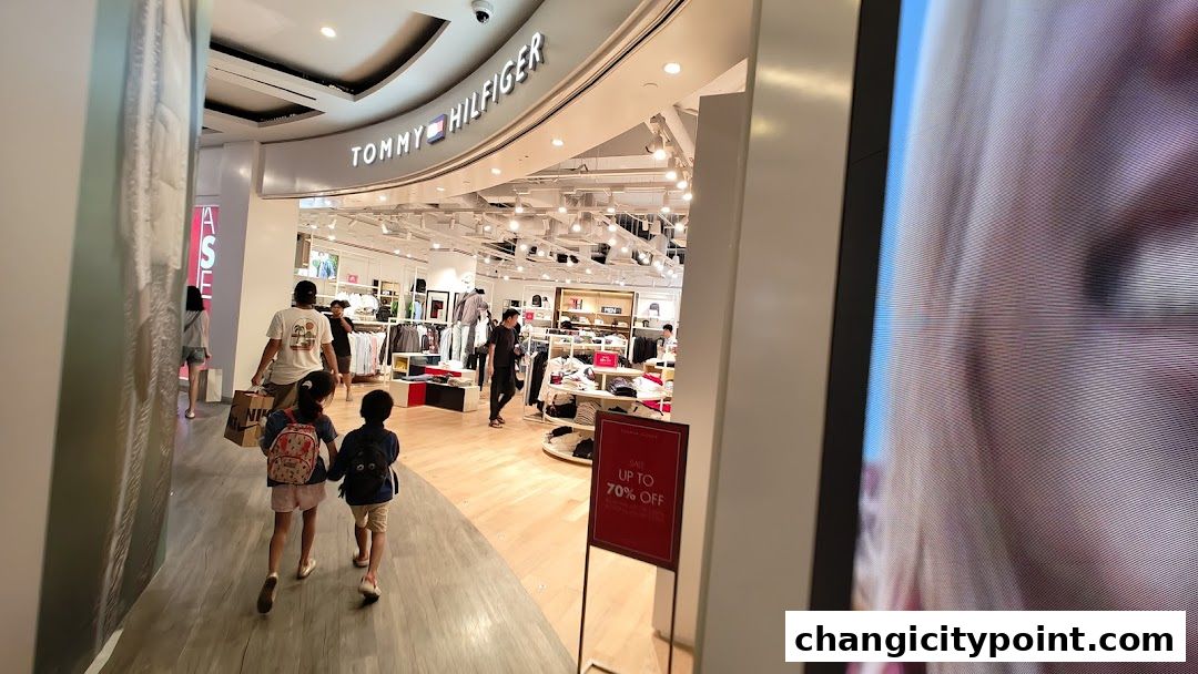 Tommy Hilfiger outlet store entrance with shoppers and sale signage.
