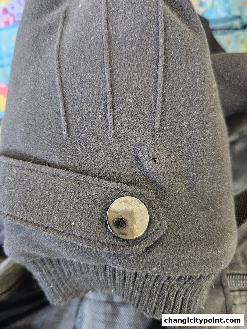 Close-up of a black jacket sleeve with a button and ribbed cuff.