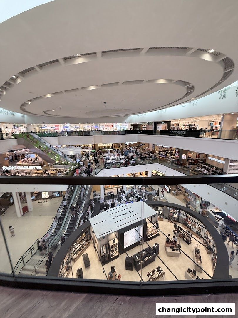 Interior view of a multi-level shopping mall with various stores and escalators.