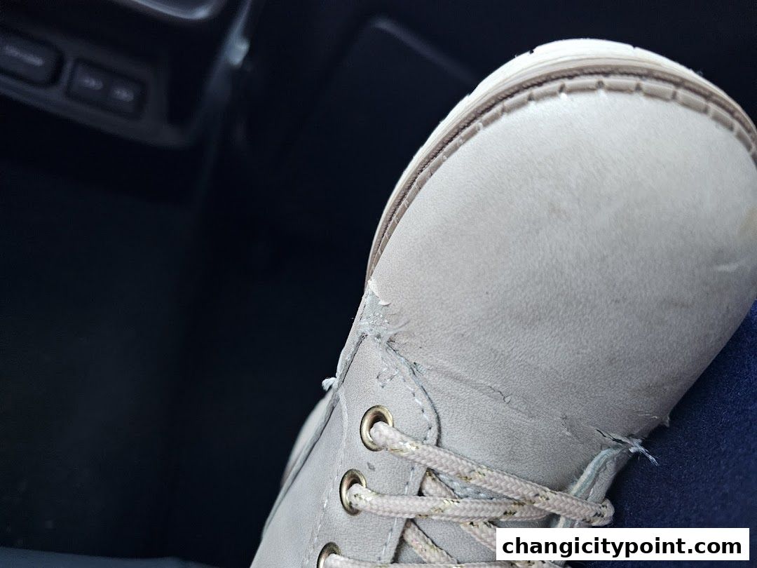 Close-up of a light-colored boot with gold-flecked laces and visible wear.