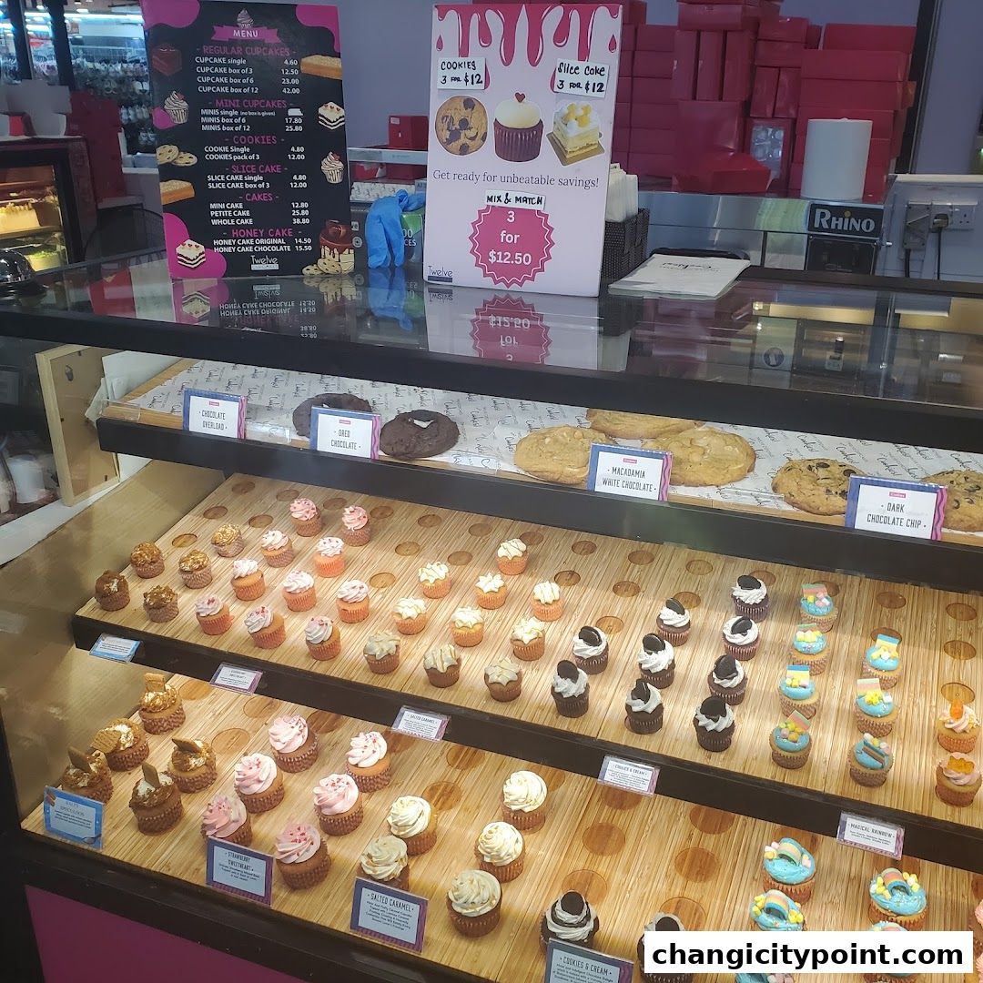 A display case filled with cupcakes and cookies, with a menu board and promotional signs.