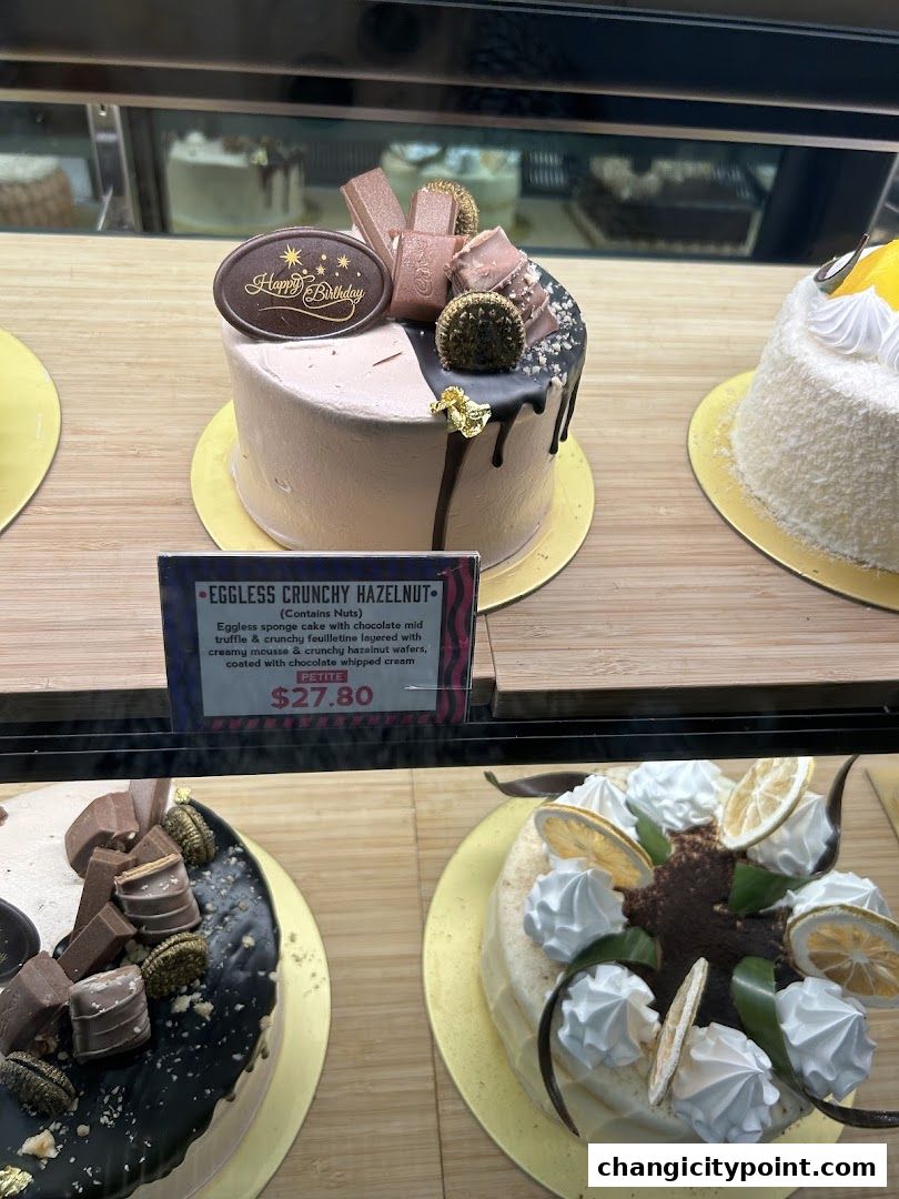 A display of beautifully decorated cakes, featuring a 'Happy Birthday' cake and other sweet treats.