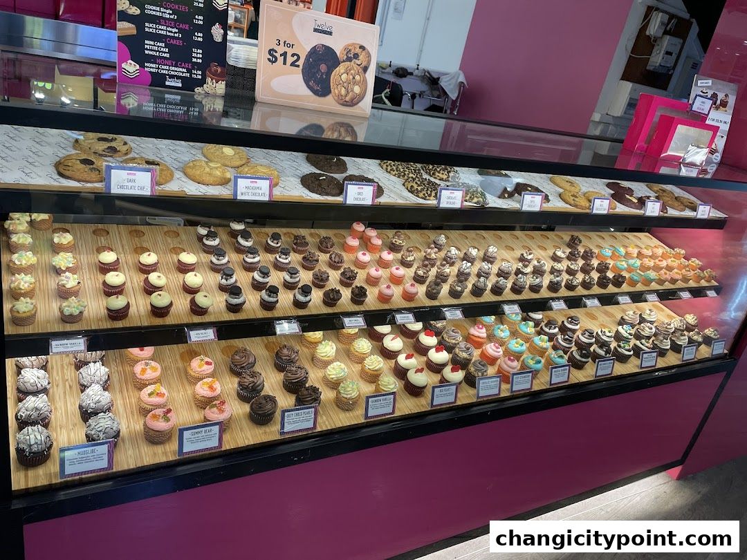 A display case filled with a variety of cupcakes and cookies at Twelve Cupcakes.