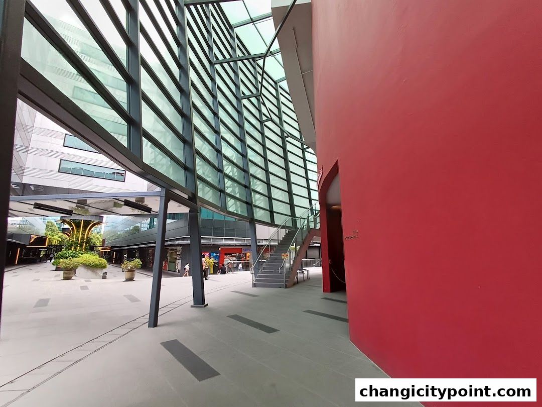Modern architectural walkway with glass facade and a vibrant red wall.