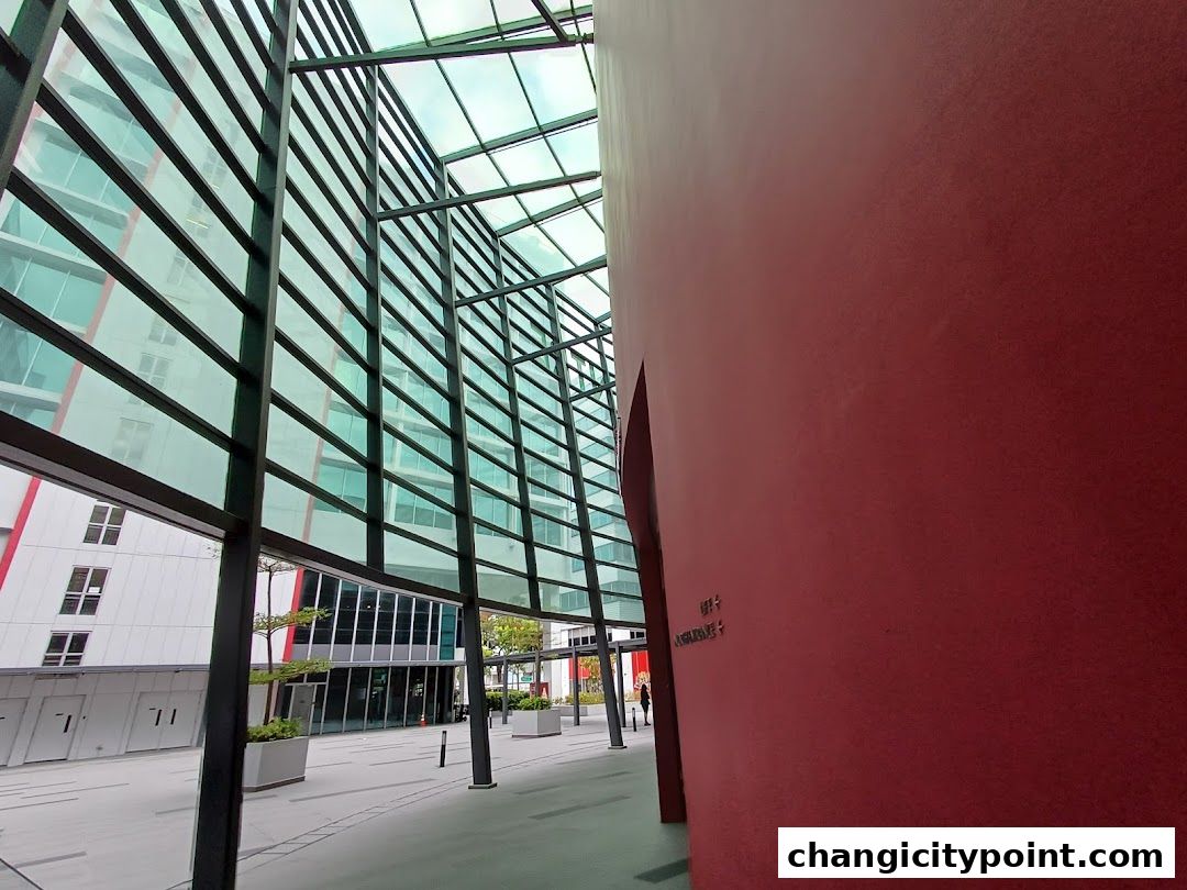 Modern architectural walkway with glass facade and a large red wall.