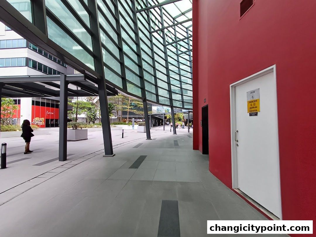 A modern walkway with a red wall and a glass-covered building.