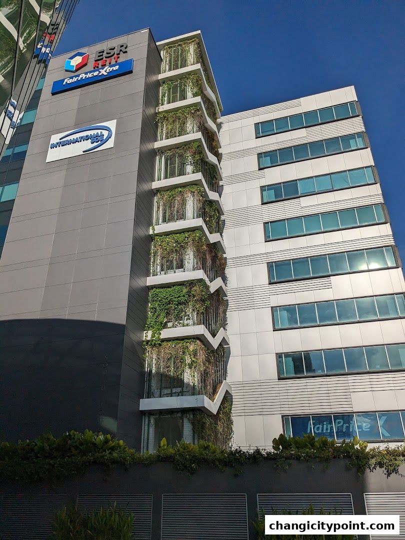 Exterior view of a modern office building with green vertical gardens and FairPrice Xtra signage.