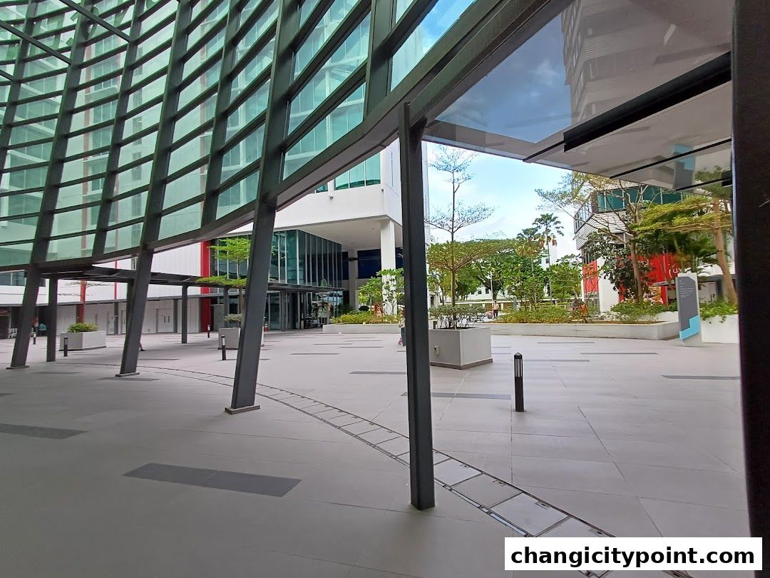 Modern architectural courtyard with glass buildings and greenery.