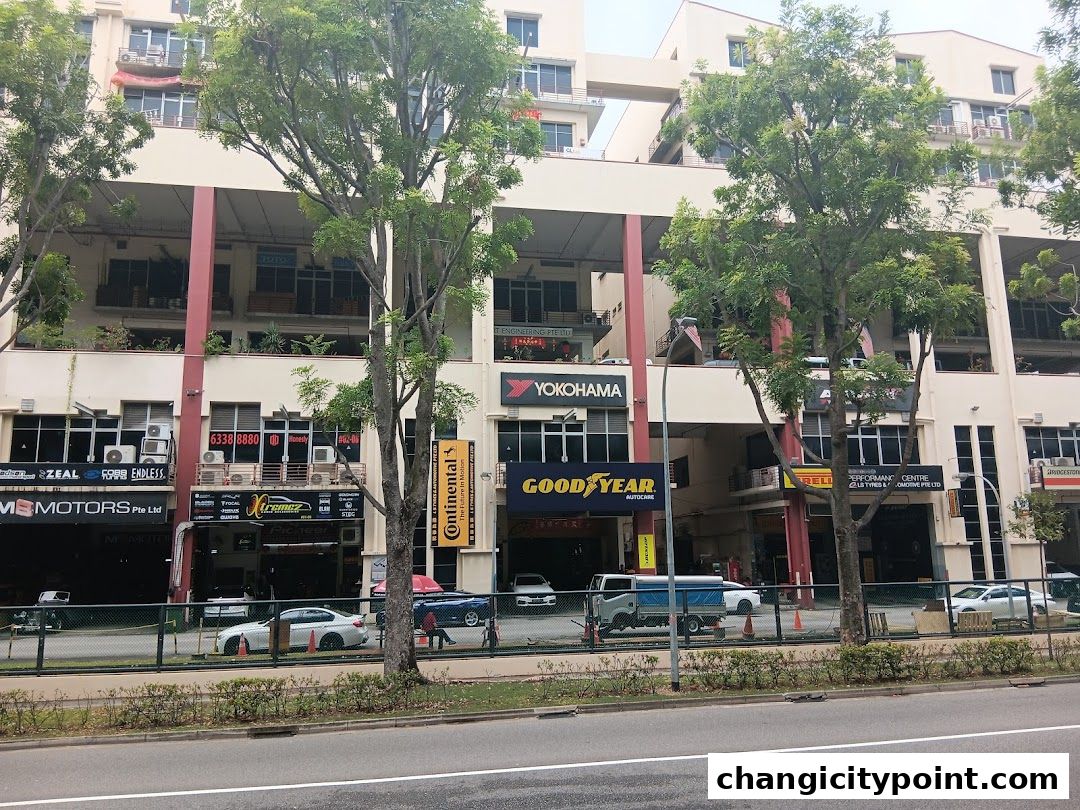 Exterior view of a row of automotive shops with various tire and car service brands displayed.