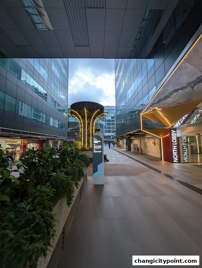 Modern walkway with lush greenery and illuminated architectural features.