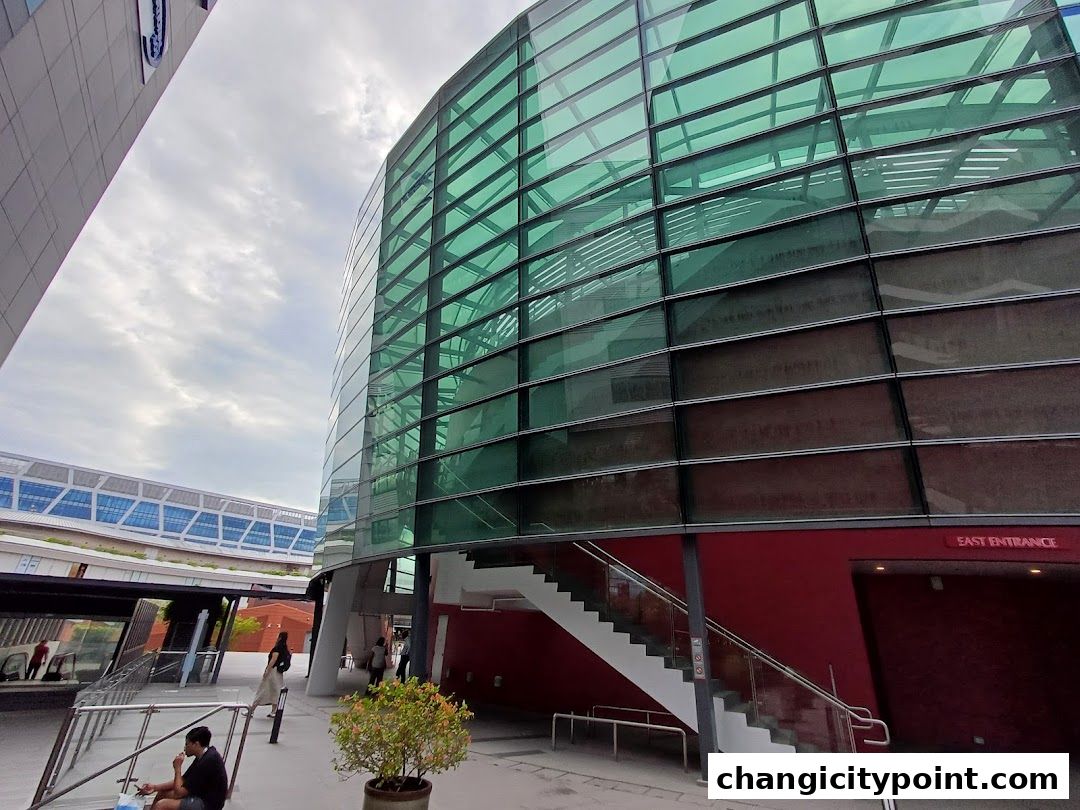 Modern building with green glass facade and red base, featuring an East Entrance.