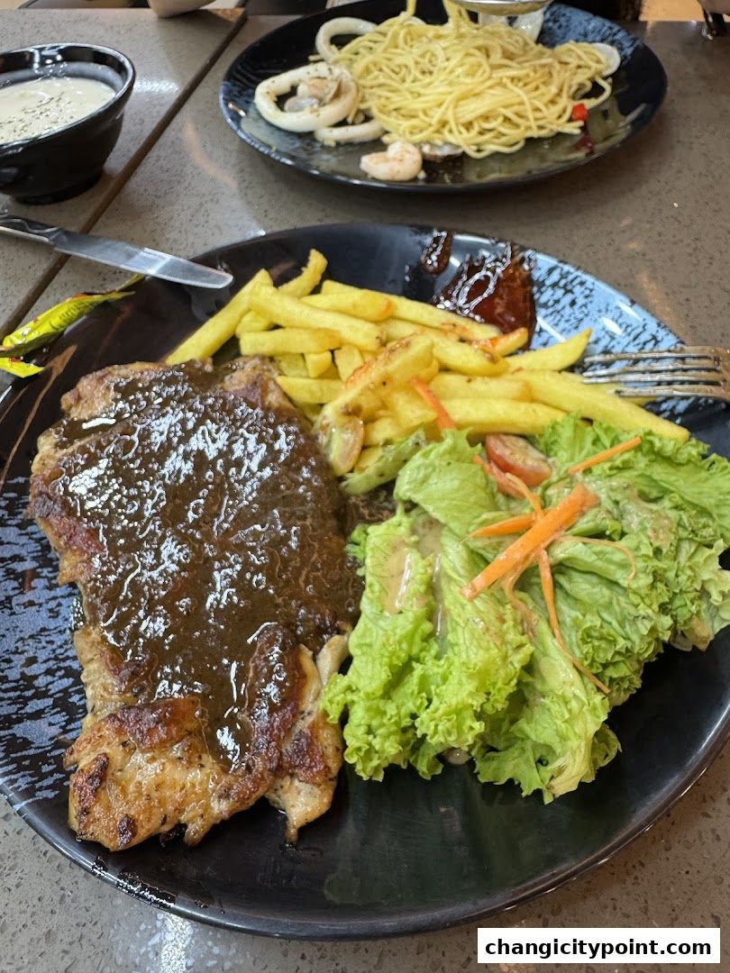 A plate of steak with fries and salad, and a plate of pasta with seafood in the background.
