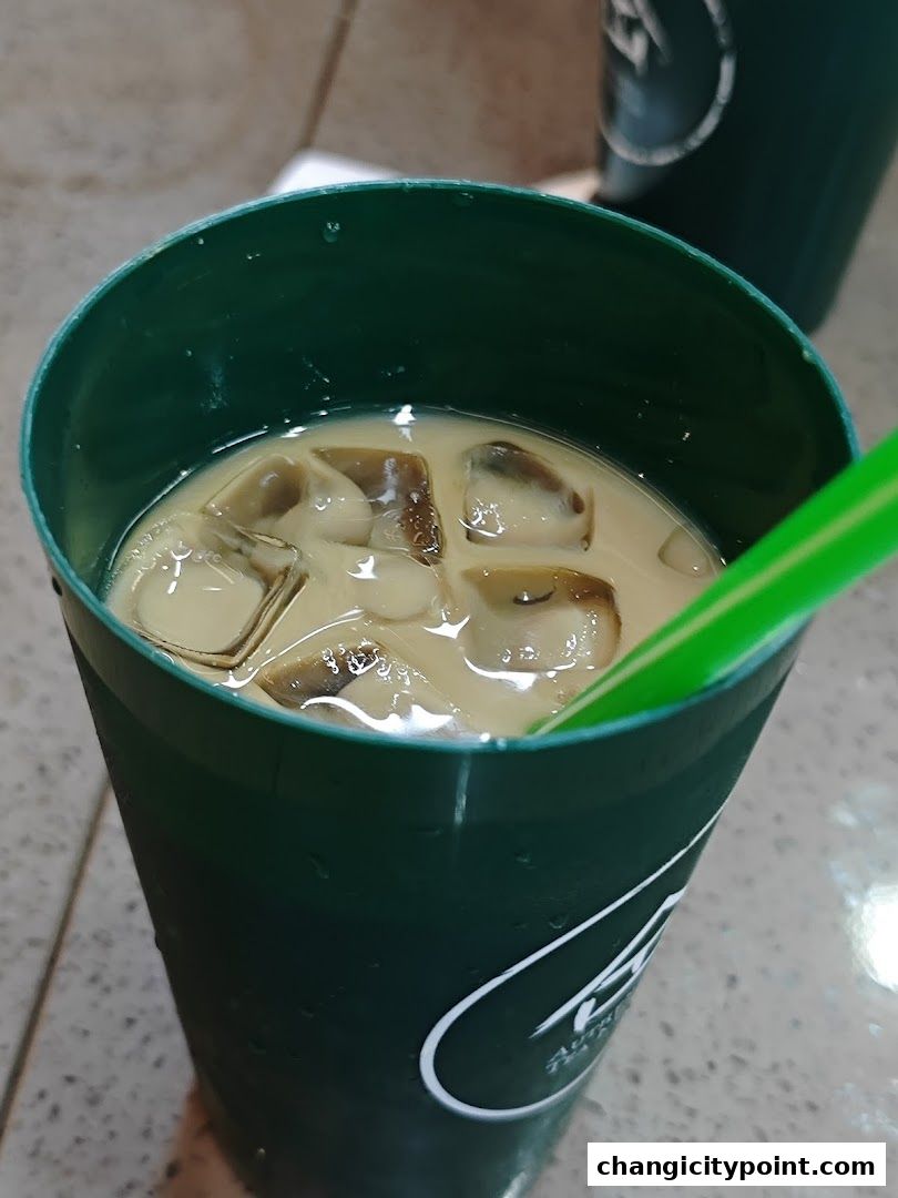 A close-up of an iced coffee in a green reusable cup with a straw.