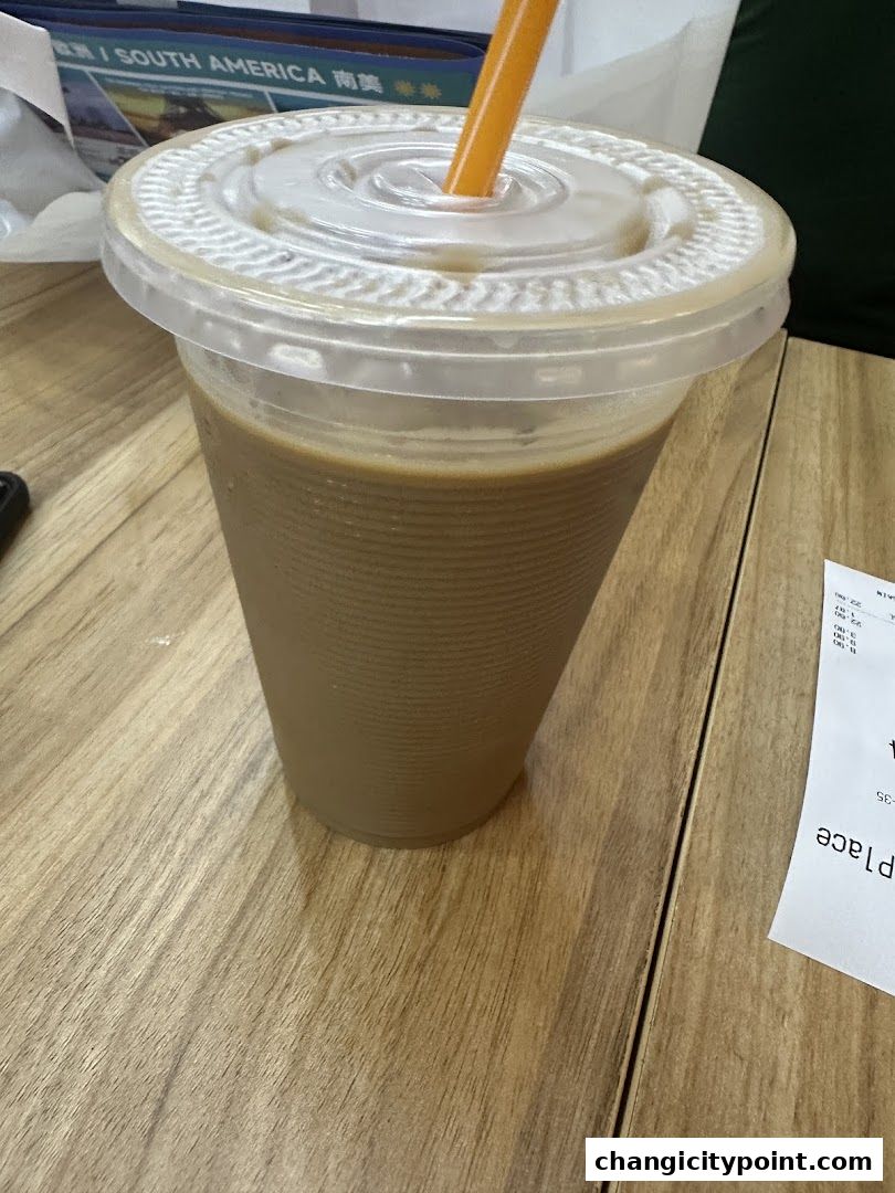 A close-up of a takeaway coffee cup with an orange straw on a wooden table.