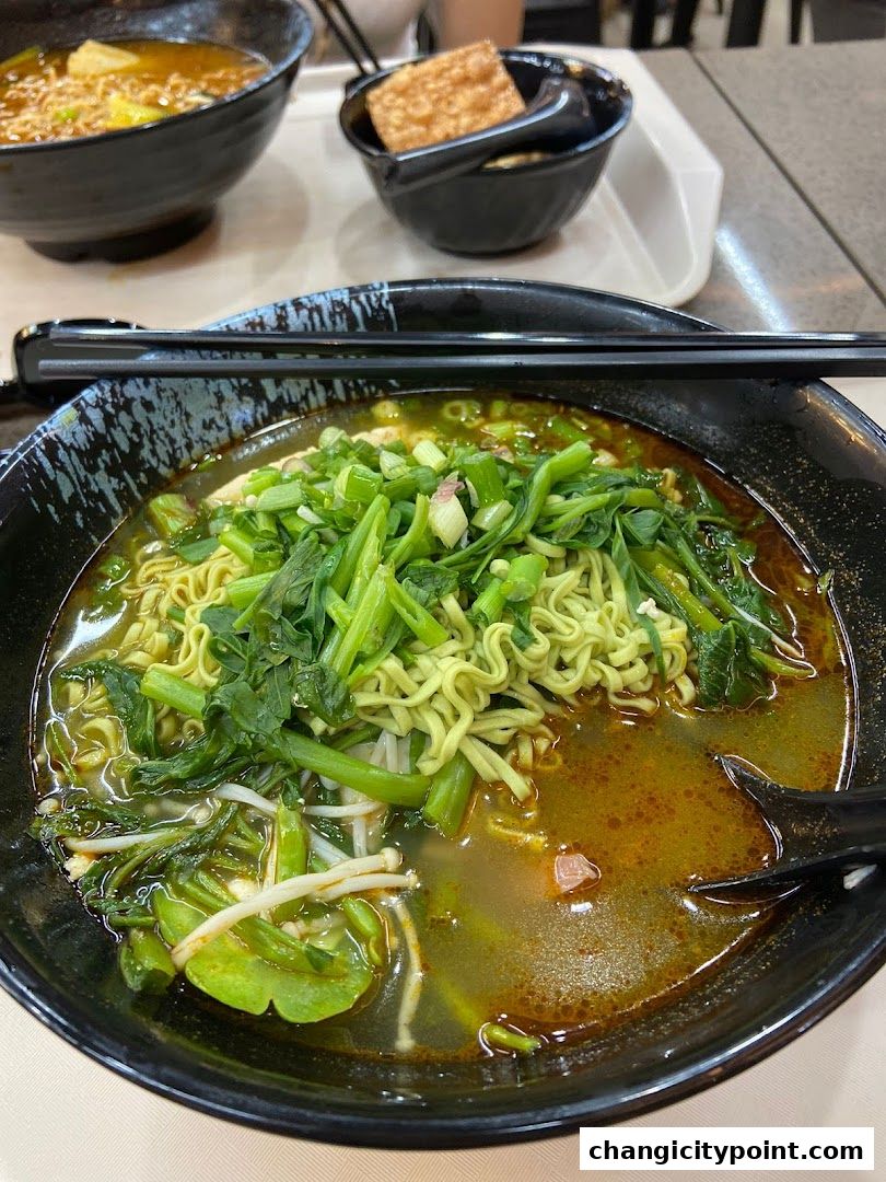 A close-up of a steaming bowl of green noodles with vegetables and broth.