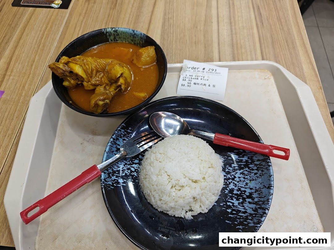 A bowl of curry chicken with potatoes and a plate of rice served at Uncle Johns Makan Place.