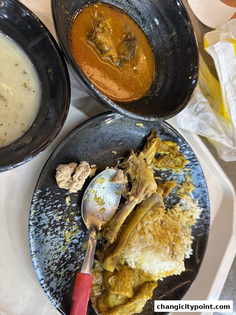 A plate of rice with chicken and curry, and a bowl of soup.