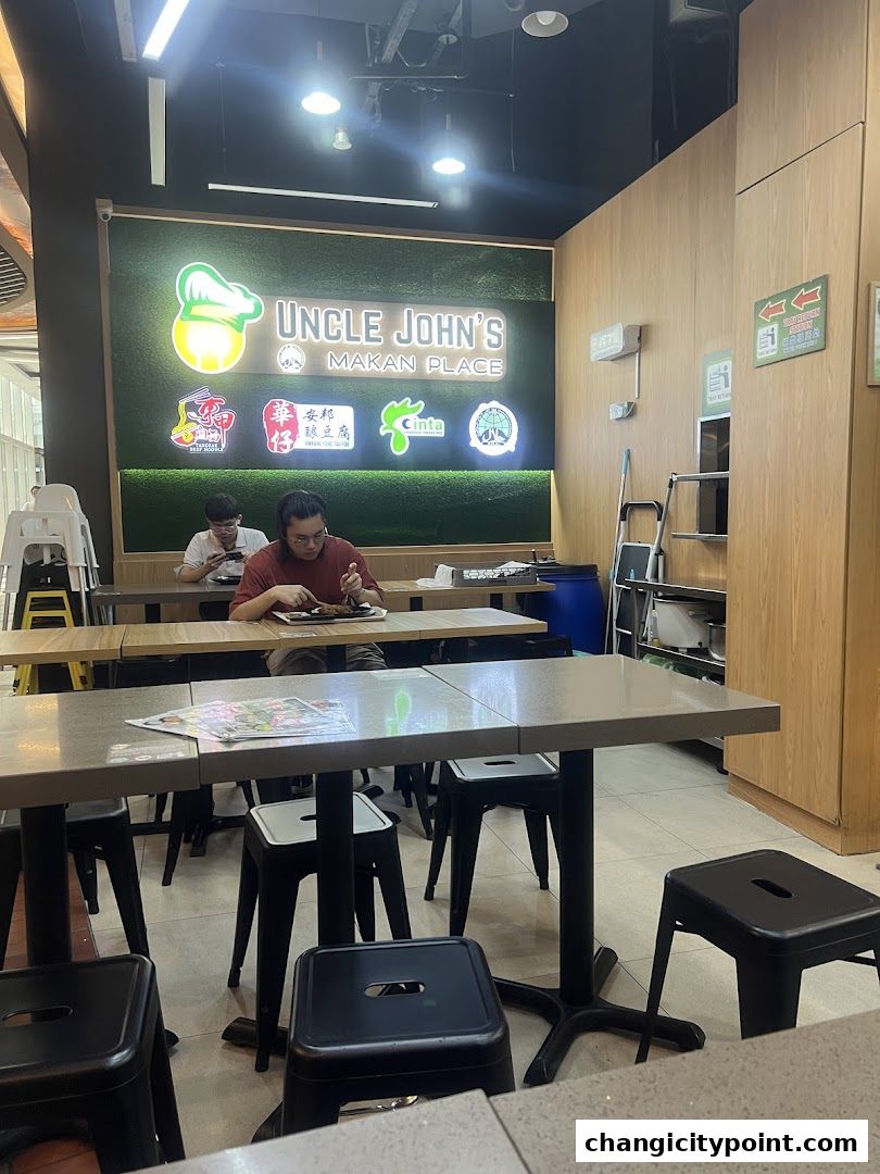 Interior of Uncle John's Makan Place with tables, chairs, and a prominent sign.