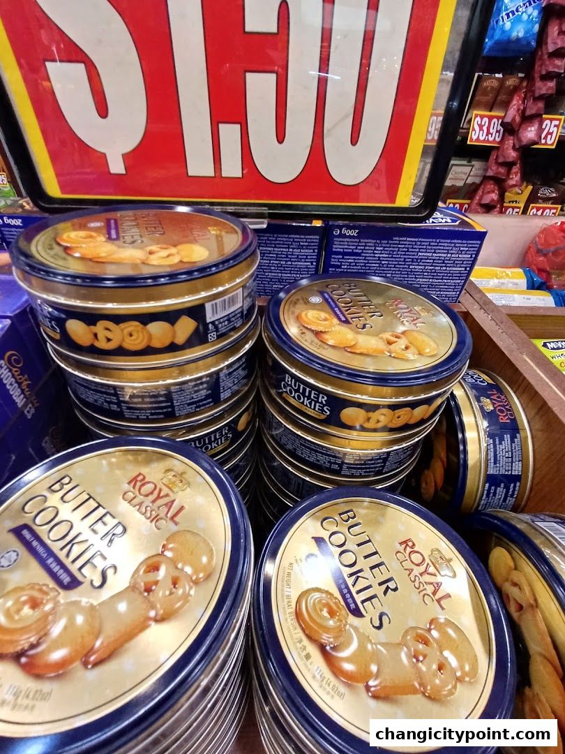 Tins of Royal Classic Butter Cookies are stacked and displayed with a price sign in the background.