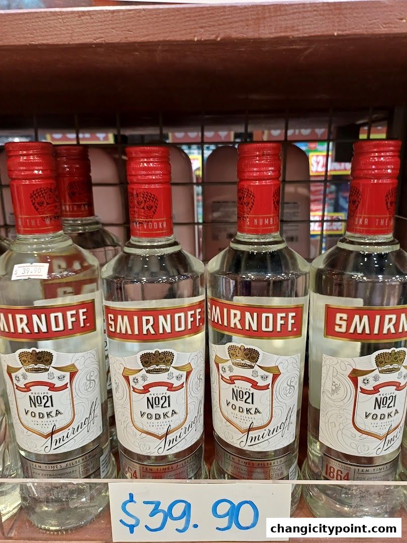 Several bottles of Smirnoff No. 21 Vodka are displayed on a shelf with a price tag.