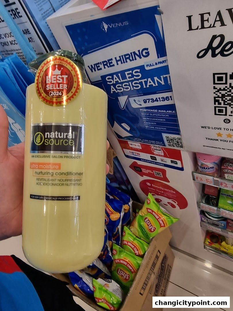 A hand holds a bottle of 'natural source' nurturing conditioner in front of a 'Venus Beauty' store display.