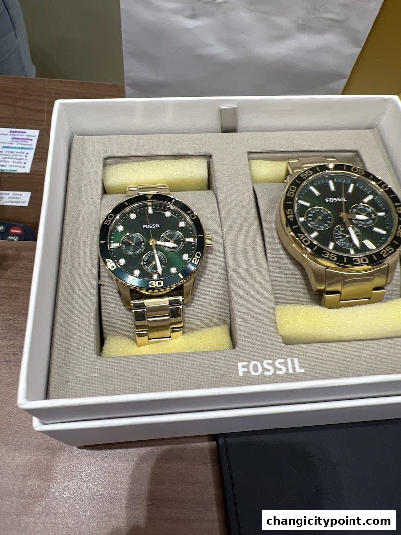 A gift box containing two elegant gold Fossil watches with green dials.