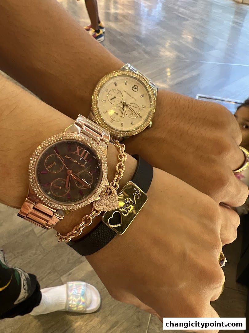 Close-up of two wrists adorned with stylish watches and bracelets.