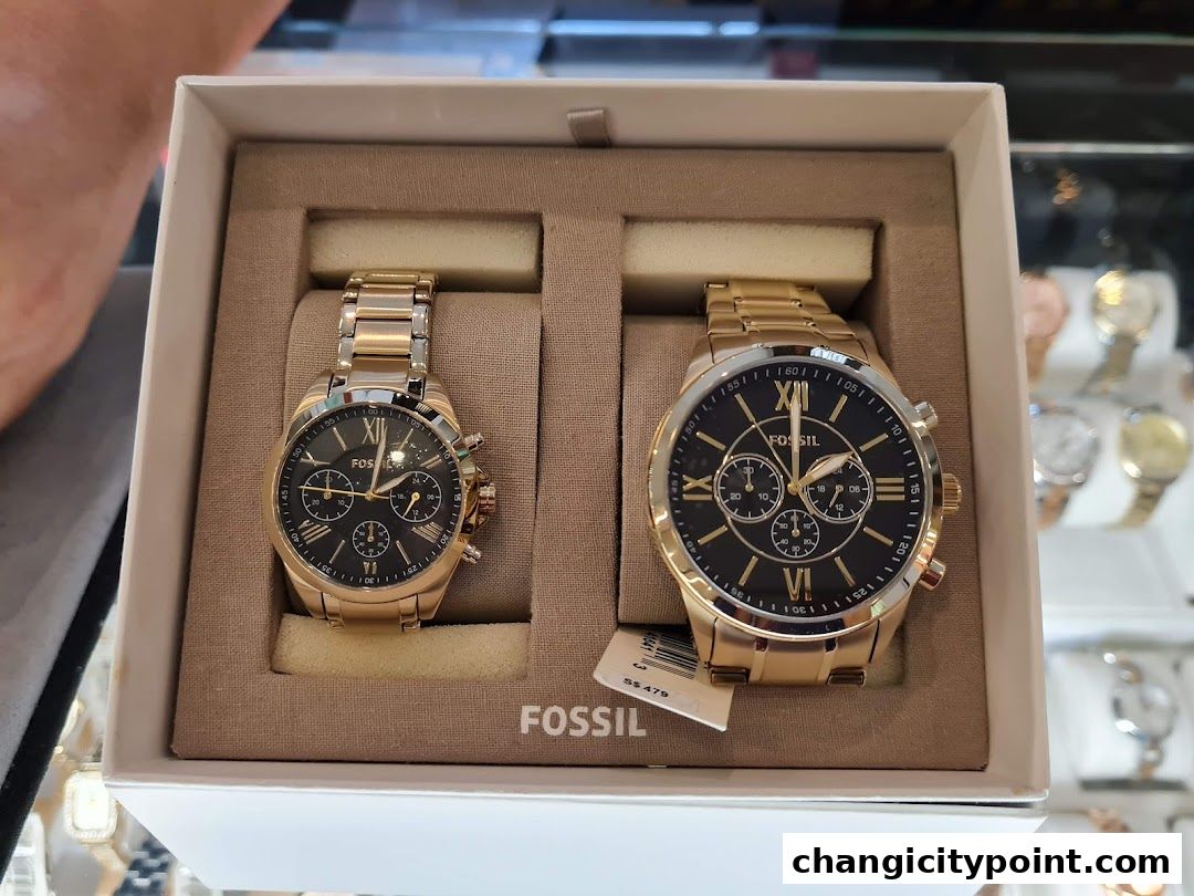 A gift box containing two elegant gold Fossil watches with black dials.