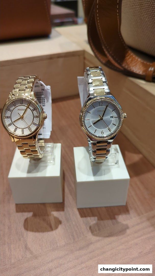 Two elegant Fossil watches, one gold-toned and one silver and gold-toned, displayed on white stands.