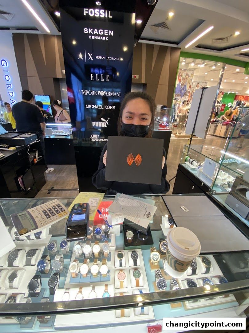 A woman holds a box in front of a display of watches and brand logos.