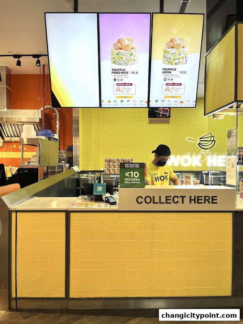 Wok Hey counter with digital menu displays and a staff member.