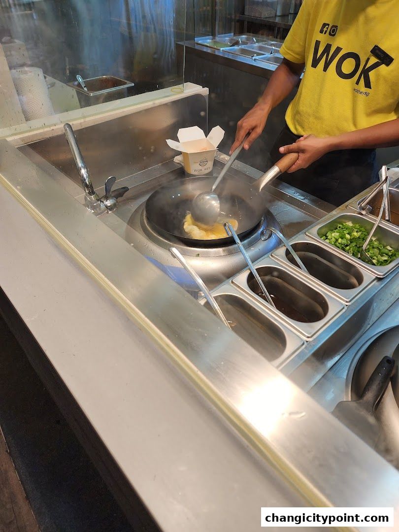 A chef cooks food in a wok at Wok Hey Changi City Point.