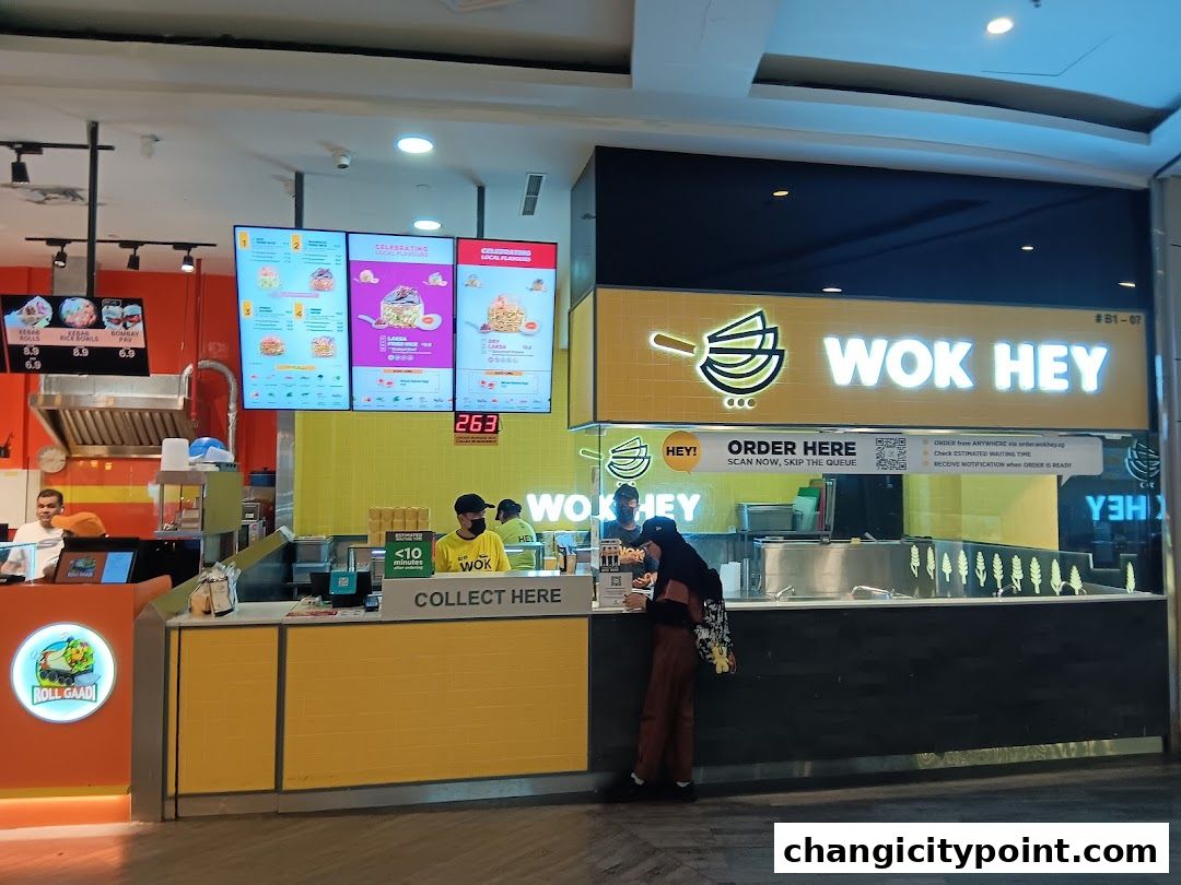 Wok Hey restaurant counter with digital menus and staff serving customers.