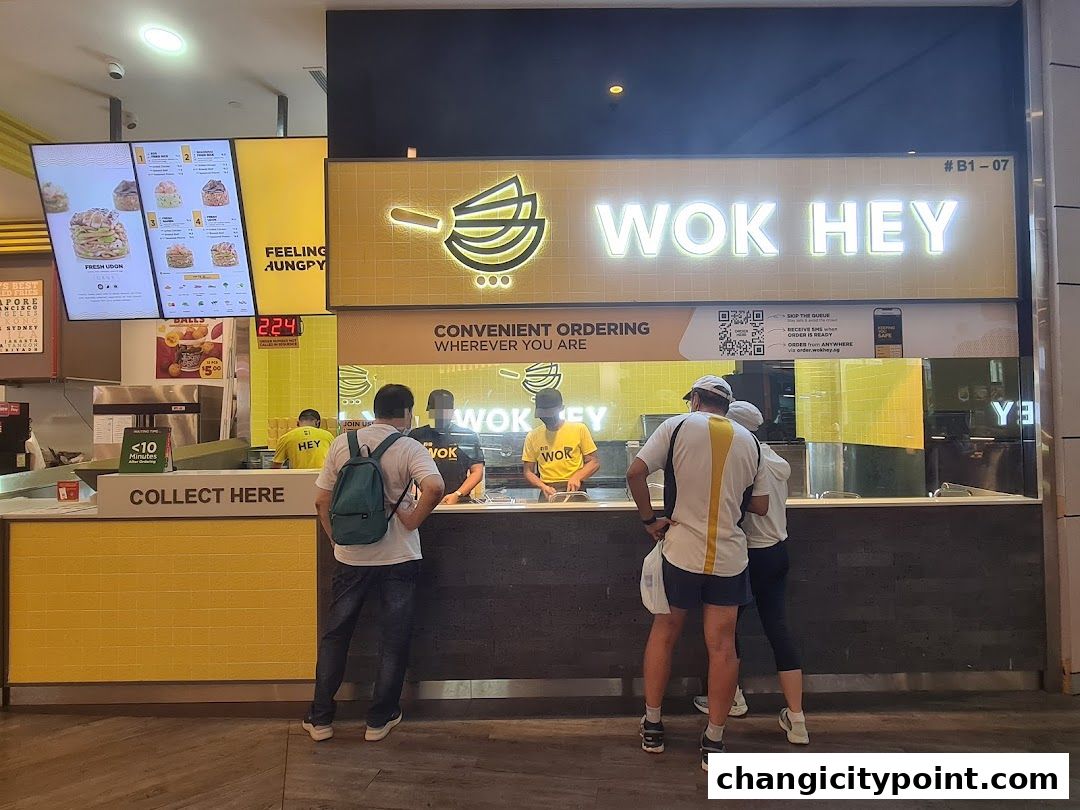 Wok Hey restaurant counter with staff serving customers and a digital menu board.