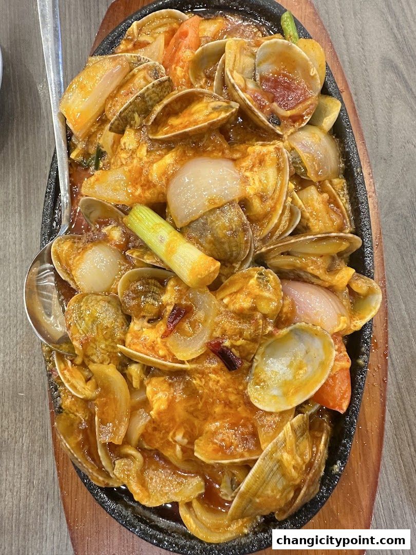 A sizzling hot plate of clams with onions and chili in a savory sauce.