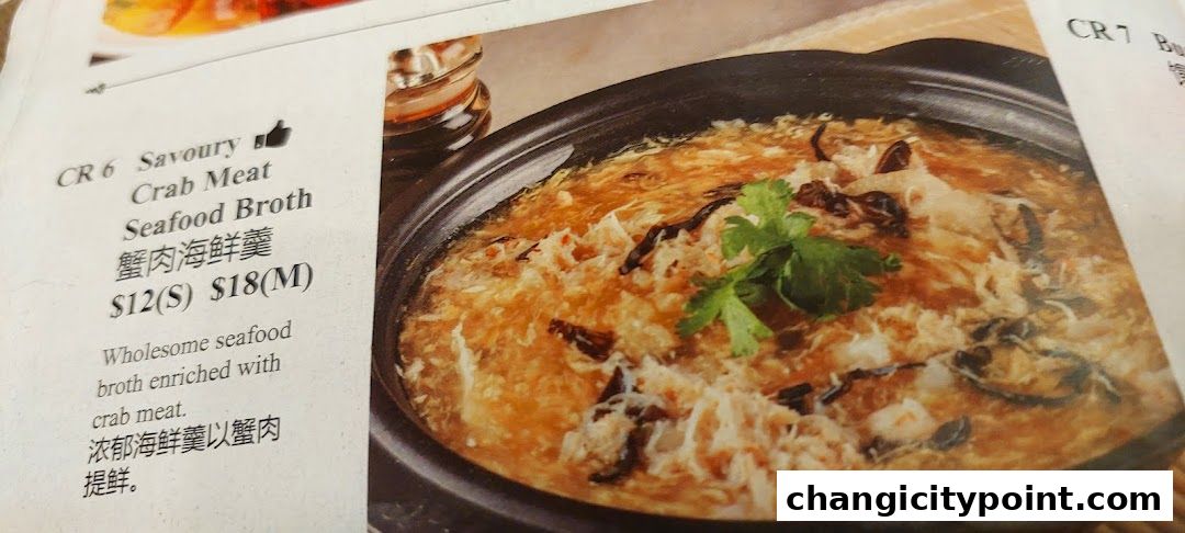 A close-up of a menu item featuring Crab Meat Seafood Broth with its description and price.