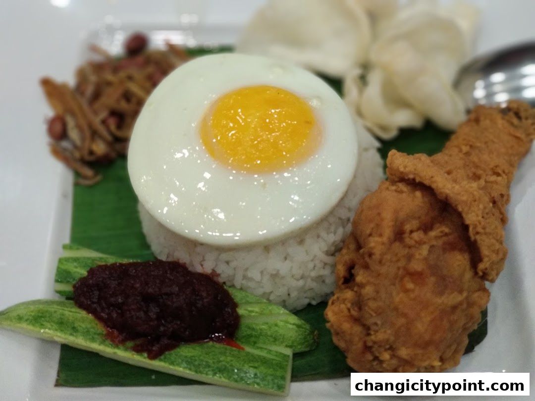 A plate of Nasi Lemak with fried chicken, sunny-side-up egg, anchovies, and sambal.