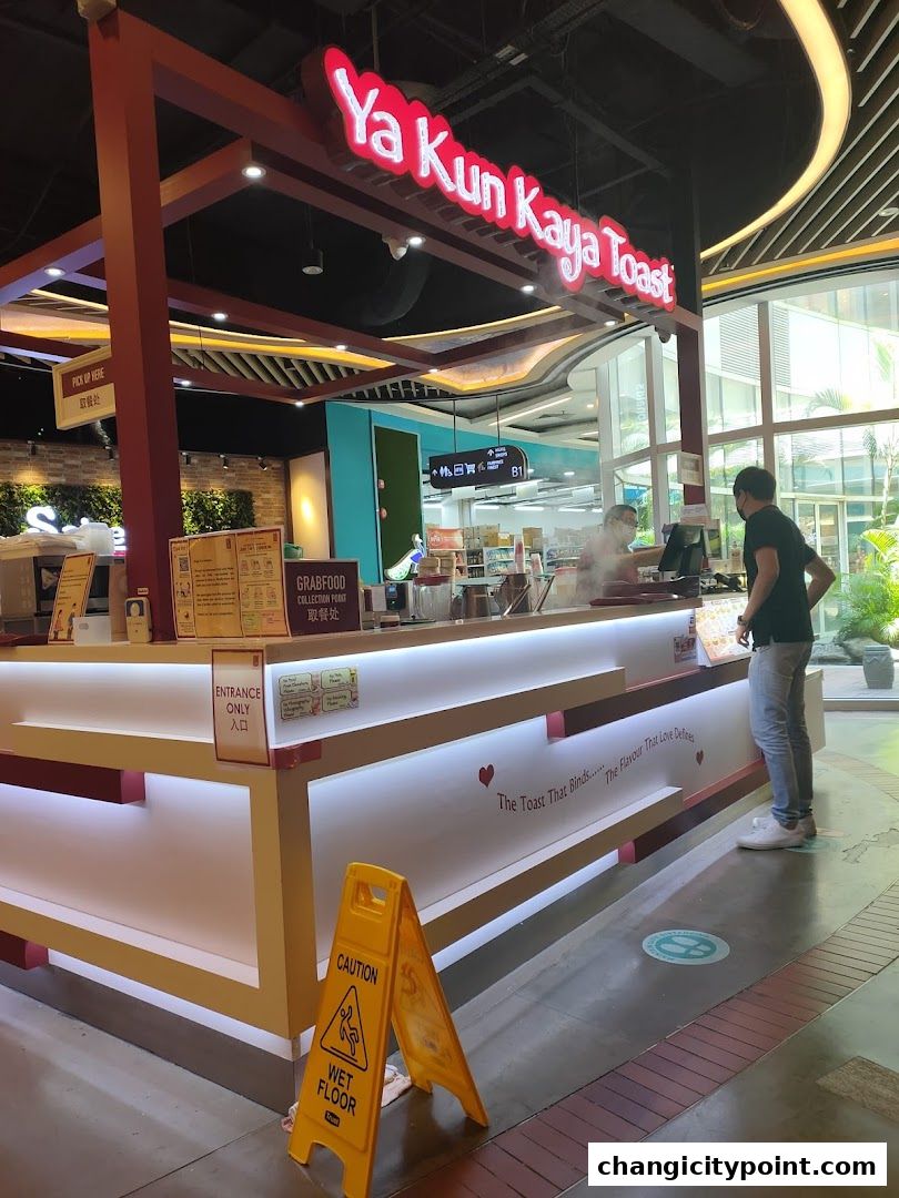 Ya Kun Kaya Toast shop counter with signage and a customer.
