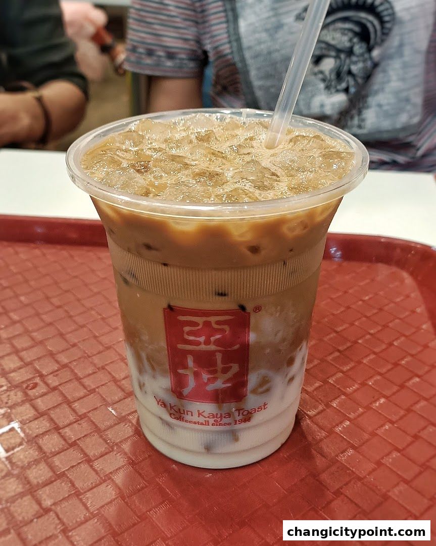 A refreshing iced coffee with milk and ice in a clear plastic cup.