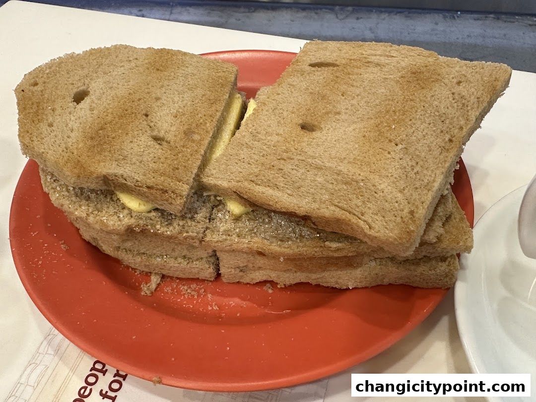 A close-up of a kaya toast with butter on a red plate.