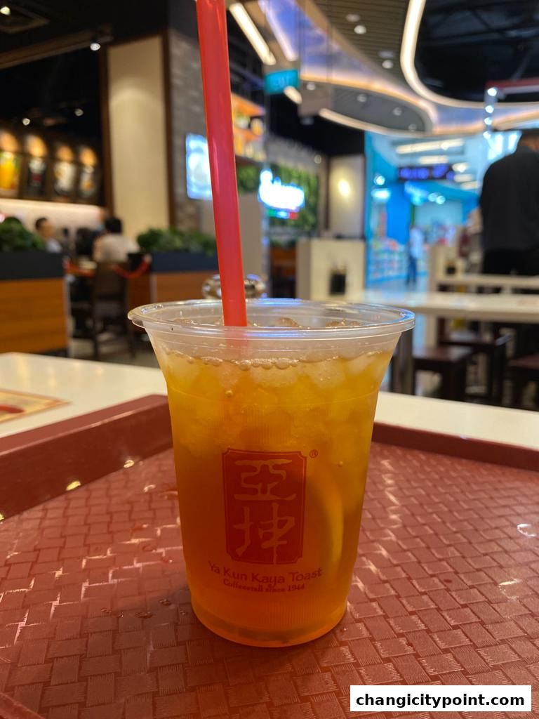 A refreshing iced tea with a slice of lemon and a red straw from Ya Kun Kaya Toast.