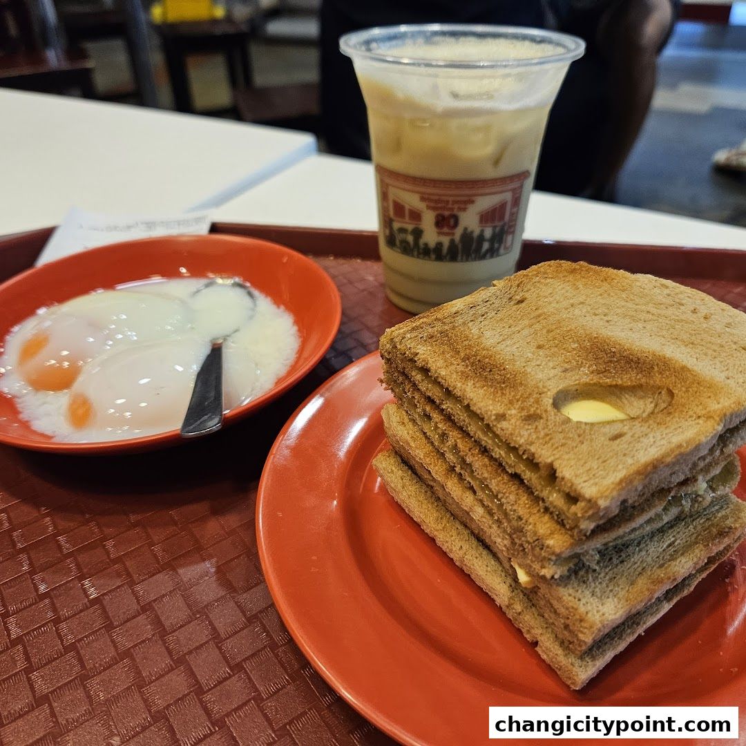 A tray with soft-boiled eggs, kaya toast, and a beverage.