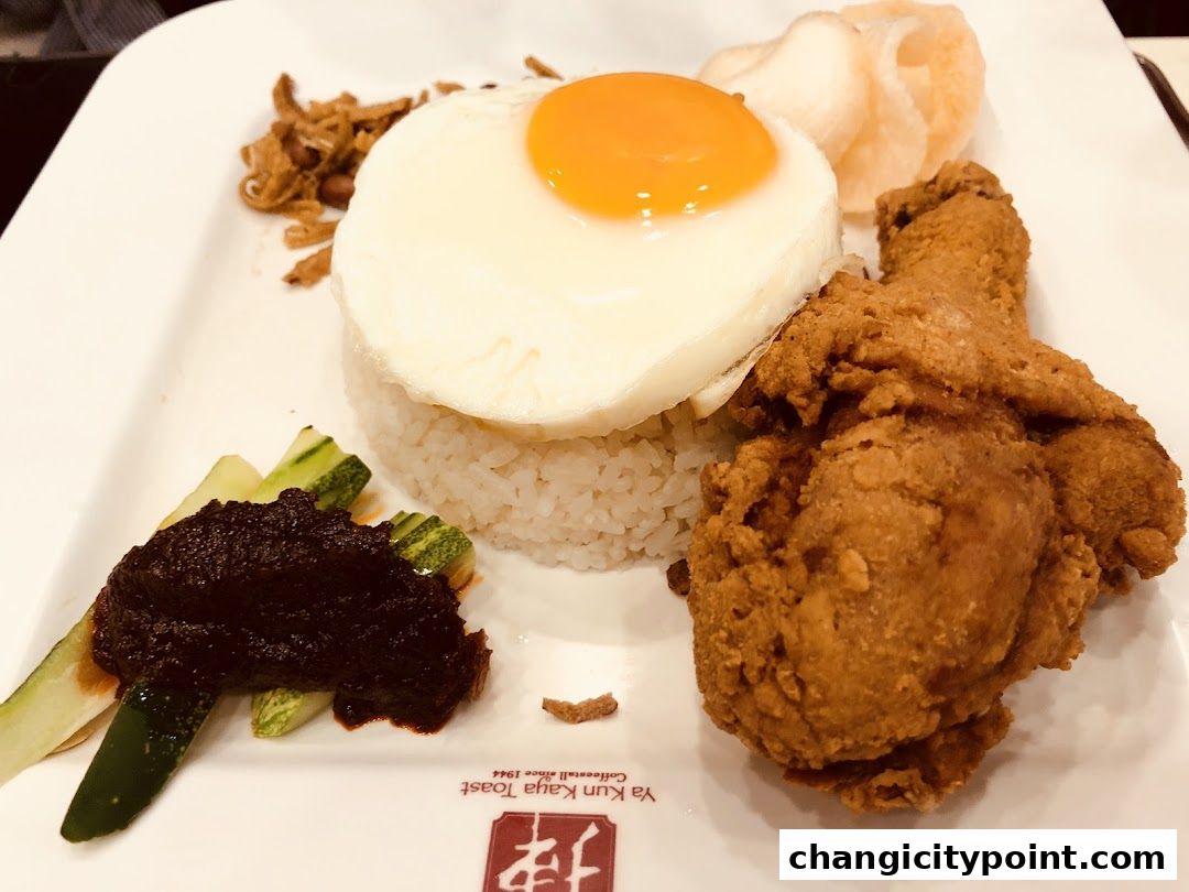 A plate of nasi lemak with fried chicken, sunny-side up egg, and sambal.