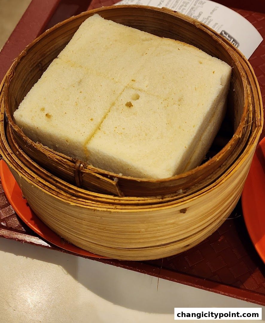 A close-up of steamed kaya toast served in a bamboo steamer basket.
