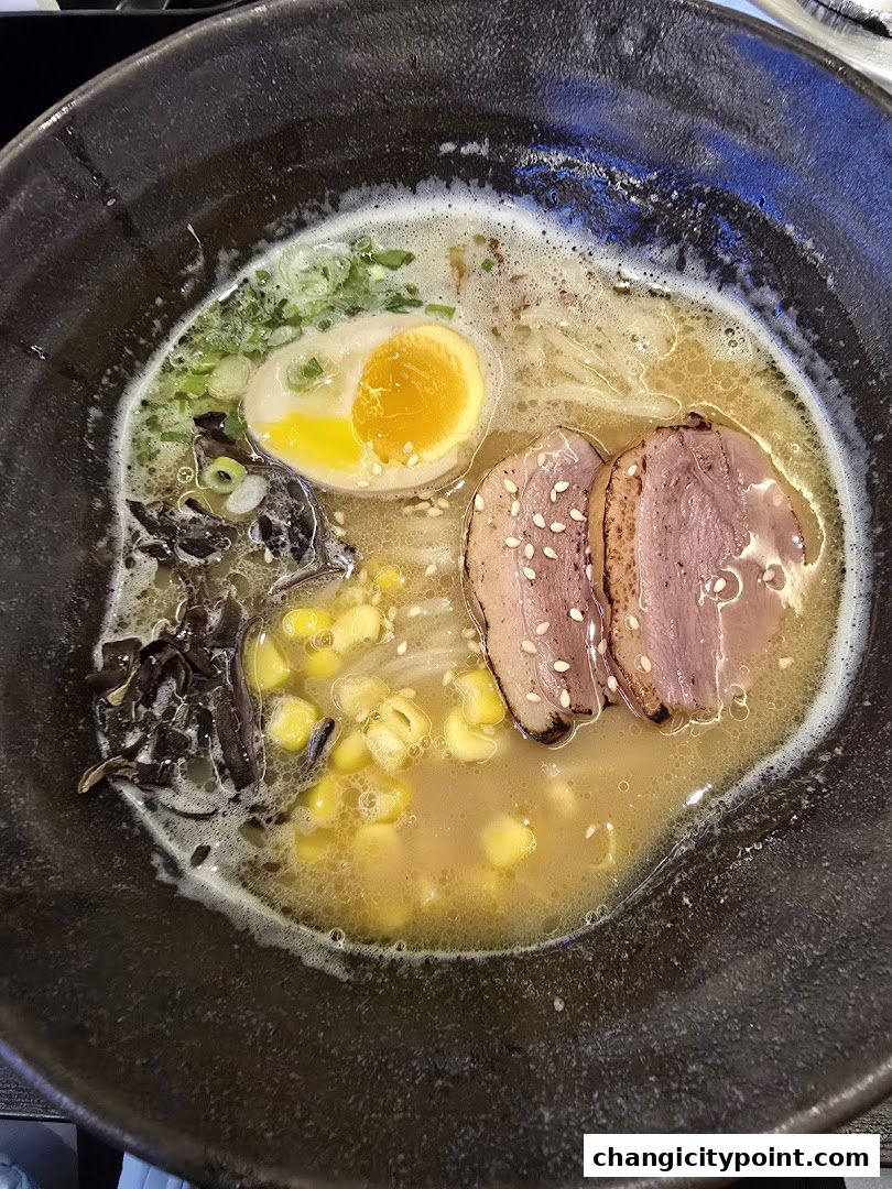 A close-up shot of a delicious bowl of ramen with pork, egg, corn, and green onions.