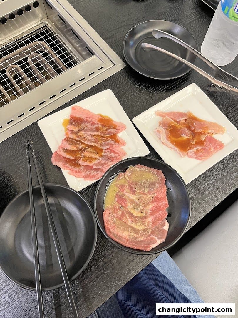 Table setting with raw meat, grill, and chopsticks at a Yakiniku restaurant.
