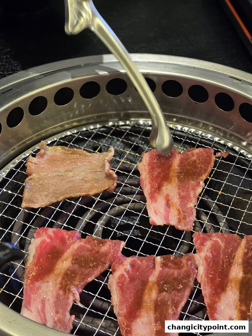 Sizzling slices of marbled beef being grilled on a barbecue grill.